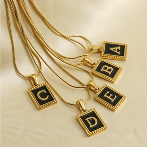 Detailed macro shot of 18K gold plated square letter pendants on sleek snake chains