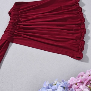 Gros plan détaillé sur un tissu plissé rouge vin avec design élastique froncé sur gris