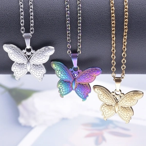 Trois colliers papillon en or, argent et arc-en-ciel sur un support d'exposition noir