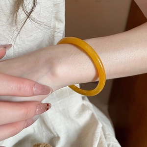 Detailed view of a yellow translucent resin bangle with smooth polished round edge design