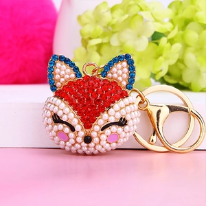 Detail of fox head keychain with red rhinestones and white pearls on golden chain