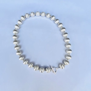 Gros plan sur collier perlé en métal brossé argenté avec fermoir à bascule OT chic