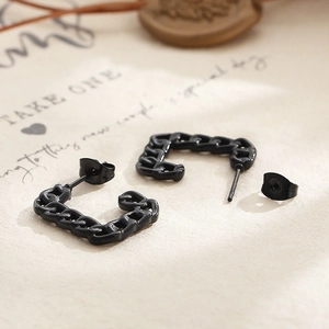 Macro shot of matte black cuban link earrings on vintage paper with decorative seal