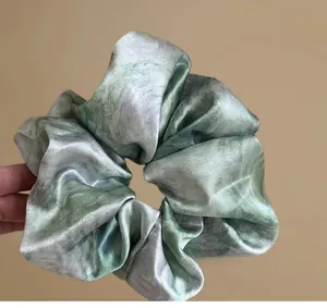 Macro detail of starry blue watercolor marble satin scrunchie with soft silk texture
