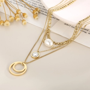 Close-up of golden multi-layer necklace featuring pearls and pavé zircon ring pendants