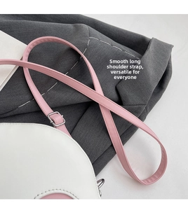Detail of adjustable pink PU leather shoulder strap with silver metal buckle on white bag
