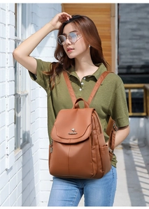 Brown soft leather backpack shown on a model in a natural outdoor architectural setting
