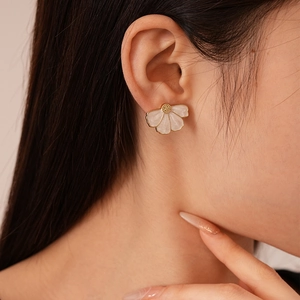 Elegant white floral stud earrings with gold edges and petal texture on model's ear