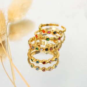 Close-up of four-piece gold ring set with multi-colored zircon stones and wavy textures