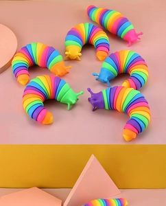 Detailed top view of six flexible rainbow fidget slugs on a soft pink and yellow background