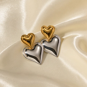Chic two-tone gold and silver heart-shaped drop earrings on champagne satin background