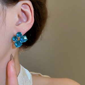 Close-up of square cut blue crystal earrings on model with 18k gold plating detail