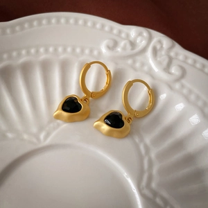 Detail of vintage gold heart earrings with matte finish and black faceted stone inlay