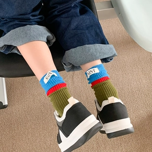 Close-up of color-block skateboard socks featuring a blue SAINT fabric label and stripes