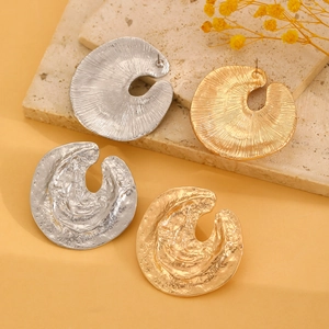 Textured gold and silver chunky earrings with irregular round relief on a stone plate