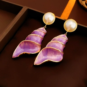 Detail of vintage purple shell earrings with gold trim and pearls in a jewelry box