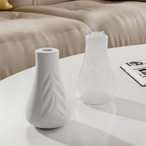 Detail of matte leaf embossed ceramic vase and translucent frosted decorative bottle
