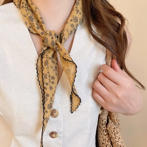 Close-up of ginger yellow floral silk scarf with scalloped black edges and flower pattern