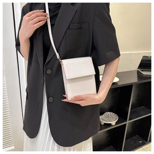 Lifestyle shot of a white PU leather crossbody bag worn over a black blazer and white skirt