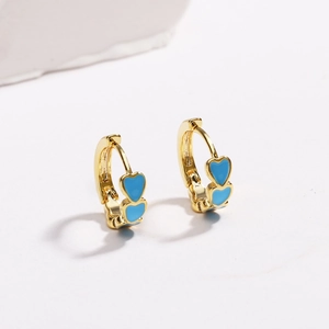 Elegant gold-plated hoop earrings with blue enamel heart charms on a white stone base