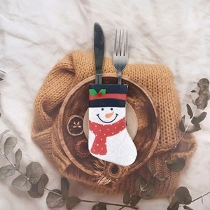 Macro shot of snowman-shaped mini Christmas stocking cutlery holder on soft knit fabric