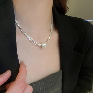 Close-up of a silver multi-layer choker necklace featuring a large round pearl pendant