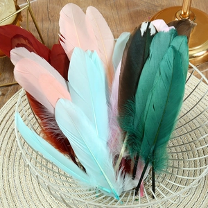 Assorted colorful goose feathers in a metal basket for DIY crafts and wedding decor