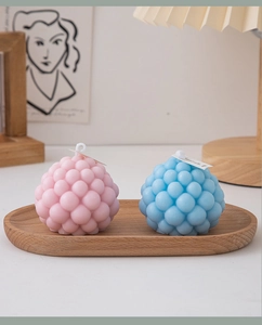 Detail view of pink and blue bubble sphere candles on an oval wooden tray with warm lighting