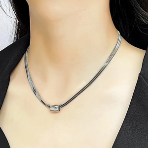 Detailed close-up of layered silver snake chain necklace with smooth oval metal bead detail