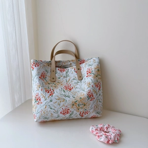 Détail du sac cabas en coton fleuri avec poignées en cuir et chouchou assorti inclus
