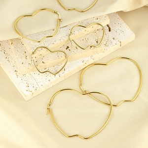 Three sizes of gold heart-shaped hoop earrings on elegant beige stone and satin fabric