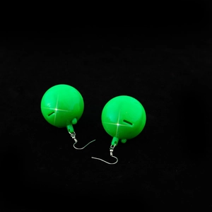 Macro shot of vibrant green disco ball earrings with reflective surface on black background