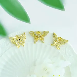 Three 18K gold plated butterfly pendants with zircon stones on a white ceramic plate