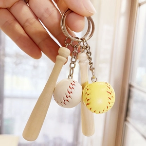 Detailed close-up of a mini wooden baseball bat and stitched ball keychain being held by hand