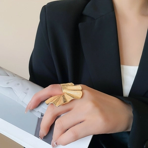 Detail of artistic golden ginkgo leaf ring with textured veins on female finger