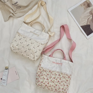 Detail of floral canvas tote bags with delicate lace trim and embroidered text decoration