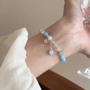 Détail d'un bracelet en perles bleues avec pendentif fleur dorée et cristaux