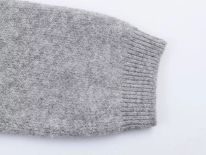 Detail of grey knitted fabric texture and ribbed cuff design on a casual sweater