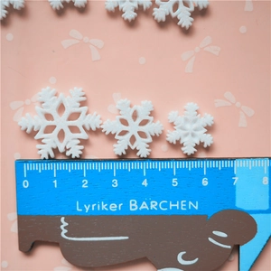 Three white glitter snowflake resin charms in various sizes shown with a scale ruler