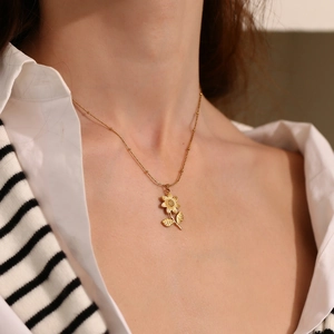 Gros plan du collier avec pendentif lotus en acier inoxydable plaqué or 18 carats au cou