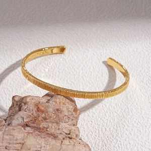 Detailed close-up of 18k gold plated bangle featuring elegant vertical texture on the band
