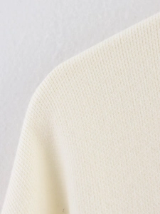 Primer plano del tejido de punto crema de alta calidad y las costuras del conjunto