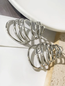 Macro shot of large multi-layered silver spiral hoop earrings on a marble tray