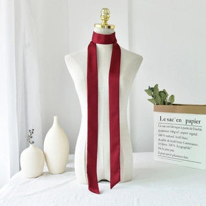 Close-up of deep red satin neck scarf tied on a white mannequin with smooth silk texture