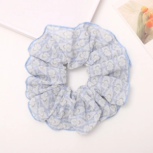 Detailed close-up of light blue floral scrunchie with white paisley print and wavy edges
