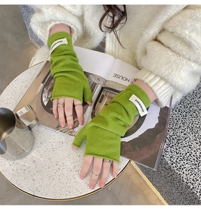 Detail of green knitted fingerless gloves with nice moment label worn by a model