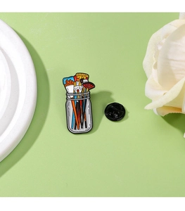 Detail of colorful paintbrush enamel pin with zinc alloy finish and black plastic clutch