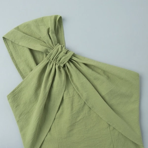 Detail of light green cotton sleeveless dress featuring a twisted knot and textured fabric