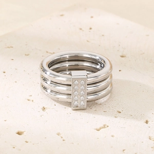 Detail shot of a silver triple-band ring with inlaid zircons on a beige stone surface