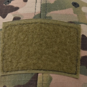 Detail of ripstop camouflage fabric with tactical hook and loop fastener area on baseball cap